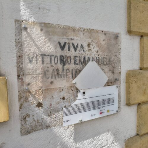 Strappato dal muro parte del pannello informativo che accompagna la scritta storica su Palazzo Arditi